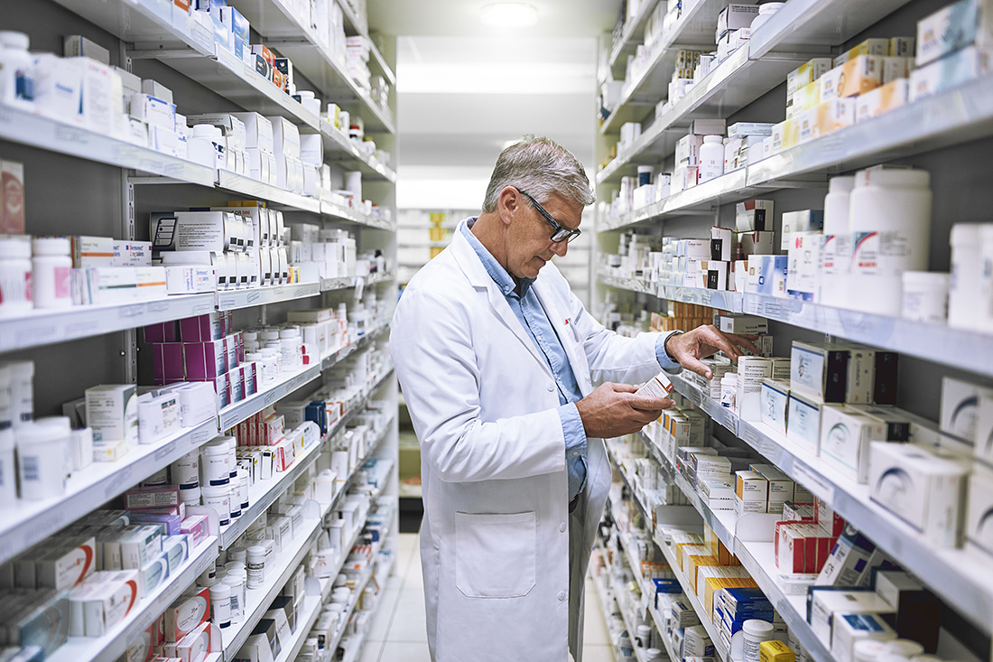  A pharmacist examines the medicine shelf in a pharmacy.