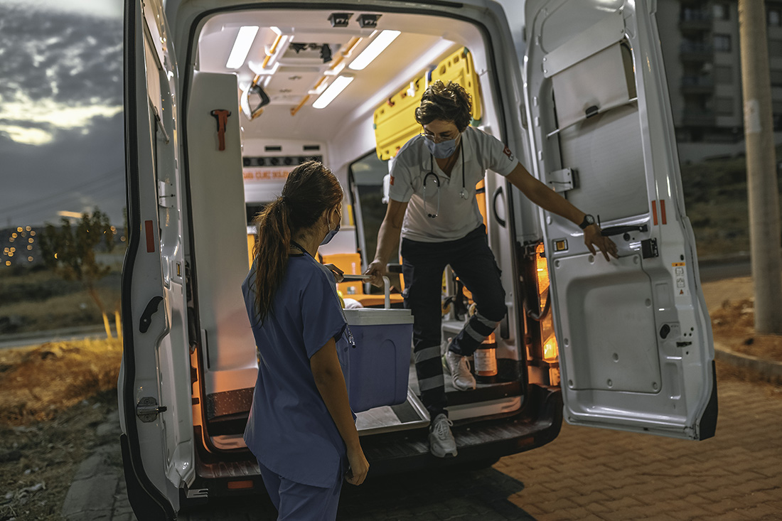Ambulanssin ensihoitaja ojentaa sairaanhoitajalle elinsiirrelaukun.